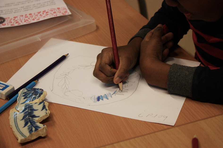 Een leerling tekent een patroon van een stuk servies af